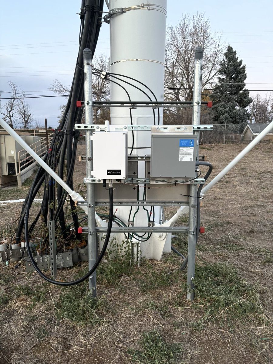 AMI collector and power enclosures mounted on a strut rack at the base of a water tank